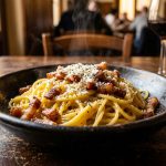 Bowl of authentic spaghetti carbonara with guanciale, pecorino romano and cracked black pepper in a rustic Italian setting