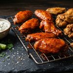 Crispy golden chicken wings on a wire rack with buffalo and dry-rub varieties, blue cheese dip and celery