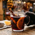 Steaming hot German Gluhwein mulled wine in a glass mug with cinnamon sticks and orange slices
