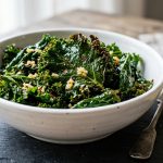 Bowl of sautéed kale with garlic and lemon, dark crispy leaves with olive oil on a slate surface