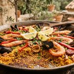 Traditional Spanish paella in a large pan with prawns, mussels, chorizo, squid and saffron rice