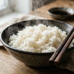 Steaming fluffy white rice in a ceramic bowl with chopsticks