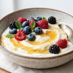Creamy yoghurt in a ceramic bowl with honey drizzle and fresh berries